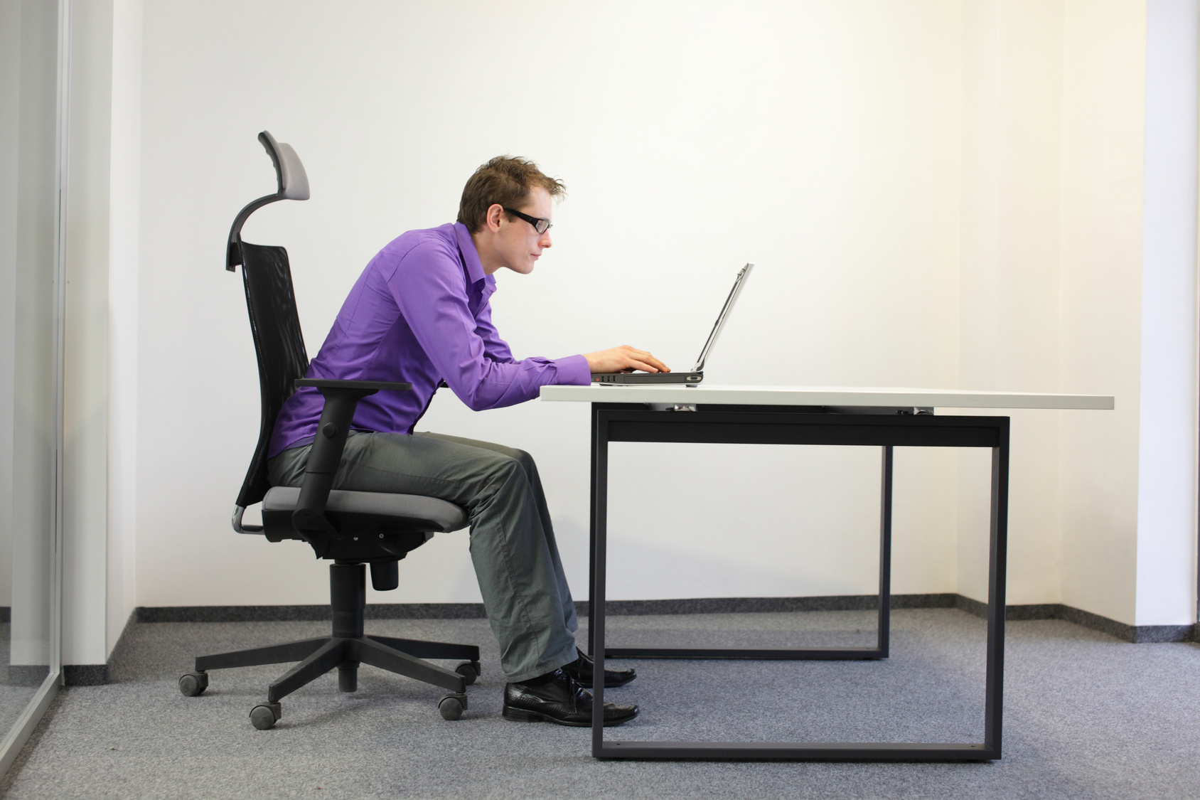 shortsighted businessman bad sitting posture at laptop